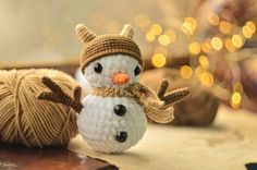 a crocheted snowman next to a ball of yarn