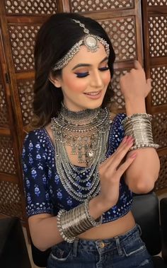 a woman in a blue top and some bracelets on her neck, wearing an elaborate headpiece