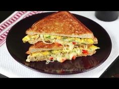 a grilled sandwich on a black plate with a cup of coffee in the background