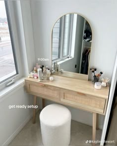 a vanity table with a mirror and stool in front of it, next to a window