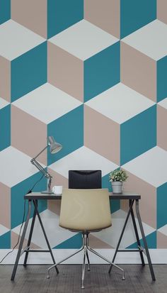 a desk with a laptop on it in front of a wall that has a geometric pattern