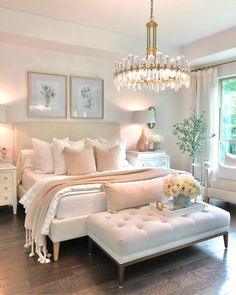 a bedroom with white furniture and chandelier hanging from it's ceiling, along with pictures on the wall