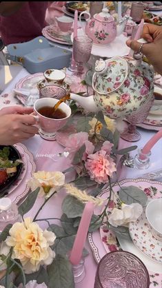 people are sitting at a table with pink and white plates, cups and saucers