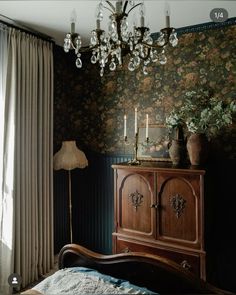 a room with a bed, dresser and chandelier hanging from it's ceiling