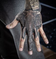 an elephant tattoo on the palm of a man's hand, with his hands painted