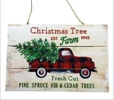 a christmas tree sign hanging from a rope on a white wooden wall with a red truck holding a small fir tree