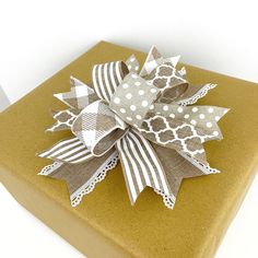 a gift wrapped in brown and white paper with a bow on it's side