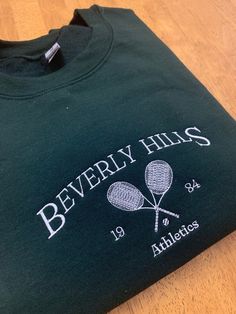 Beverly Hills Embroidered Sweatshirt  Available in other colors  ✰This item is MADE TO ORDER and can be shipped out within a week ✰Colors may vary due to color variations in monitors ✰All of the crewnecks are unisex and made of polyester and cotton material ✰These crewnecks are machine embroidered with 🫶 ✰Size up for oversized fit  ✰Please message me if you have questions about your order! ✰All sales are final Size Guide Length/Width Small- 27/20 in. Medium- 28/22 in. Large-29/24 in. XL-30/26 i Collegiate Cotton Sweatshirt With Screen Print, Varsity Cotton Sweatshirt With Screen Print, Sporty Embroidered Crew Neck T-shirt, Green Crew Neck T-shirt With Custom Embroidery, Crew Neck Sweatshirt With Embroidered Logo, Crew Neck T-shirt With Custom Embroidery, Cotton Sweatshirt With School Spirit Screen Print, Crew Neck Top With Embroidered Logo For College, Sporty Embroidered Long Sleeve T-shirt