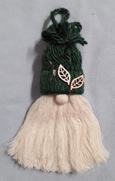 a green and white knitted hat hanging from a hook on a gray background,