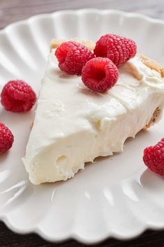 a white plate topped with a piece of pie and raspberries on top of it