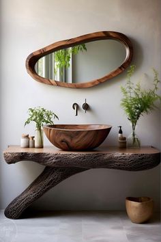 a wooden sink sitting under a mirror next to a vase filled with green plantes