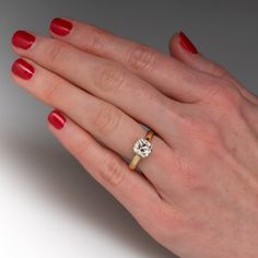 a woman's hand with red nail polish holding a diamond ring