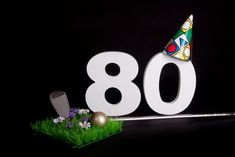 a birthday hat sitting on top of the number eighty eight with flowers in front of it