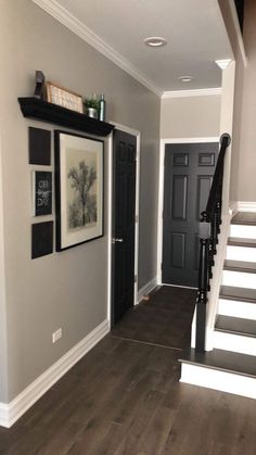 an empty hallway with stairs and pictures on the wall, framed in black and white