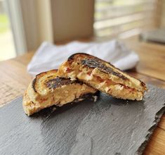 two pieces of grilled cheese sitting on top of a slate board next to a napkin