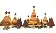 wooden christmas trees are lined up on a white surface with wine glasses in the foreground