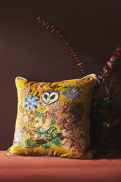 a yellow pillow sitting on top of a bed next to a vase filled with flowers