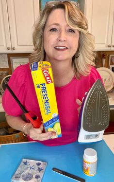 a woman is holding up a box of toothpaste and a pair of scissors