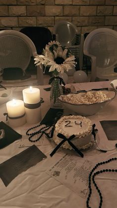 a table topped with a cake next to two candles and flowers on top of it