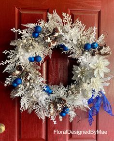 a wreath with blue and white ornaments hanging on a red door