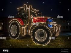 a tractor decorated with christmas lights at night - stock image