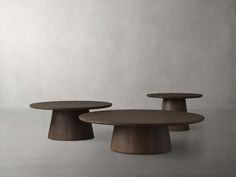 three wooden tables sitting next to each other on top of a cement floor with white walls in the background