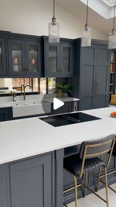 a kitchen with gray cabinets and white counter tops, an island in the middle is surrounded by bar stools