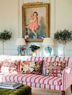 a living room with striped couches and lamps on the wall next to potted plants