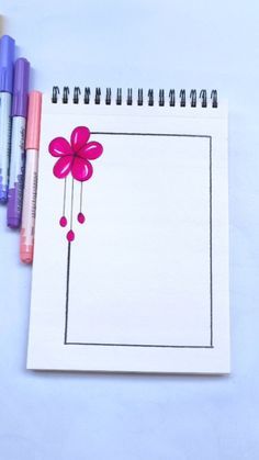 three markers and a notebook with a flower drawn on it