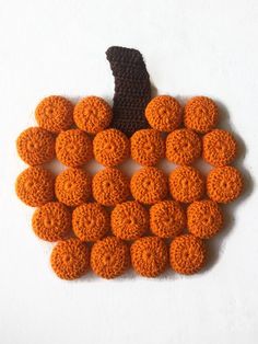 an orange crocheted pumpkin sitting on top of a white cloth covered tablecloth