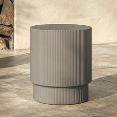 a grey vase sitting on top of a cement floor