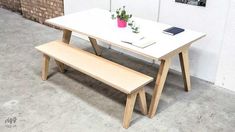 a white table with a bench next to it in front of a brick wall and potted plant