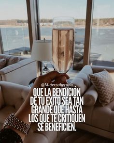 a person holding a wine glass in front of a window with the words, que la bendicion de te exito sia tan grande de los criteros entre