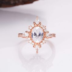 a ring with an oval cut diamond surrounded by small white and pink diamonds on top