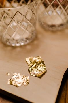 gold flakes are on a cutting board next to two glass vases and one is empty