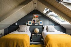 two beds in a loft with yellow blankets