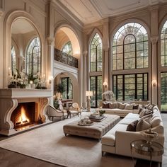 a large living room with high ceilings and arched windows, along with a fire place in the center