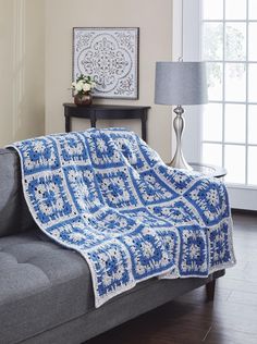 a blue and white crocheted afghan on a couch in front of a window