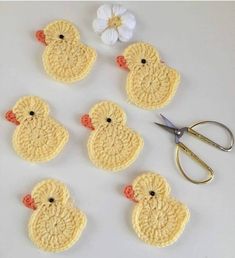 several crocheted chicks sitting on top of a table next to a pair of scissors