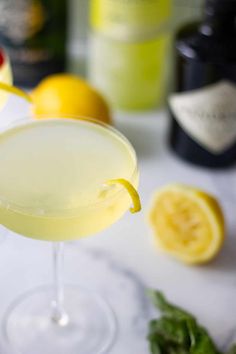 a close up of a drink on a table with lemons and other drinks in the background