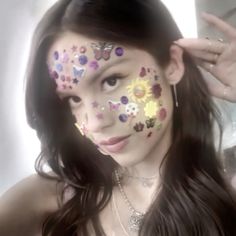 a woman with butterflies painted on her face posing for the camera and holding her hand up to her head