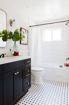 a bathroom with black and white tile flooring and walls, along with a large mirror on the wall