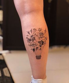 a woman's leg with flowers in a vase tattoo