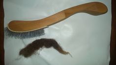 a close up of a brush and hair on a white surface