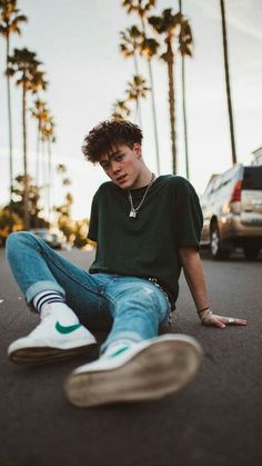 a young man is sitting on the street