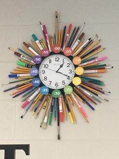 a clock made out of crayons and markers hangs on the wall next to numbers