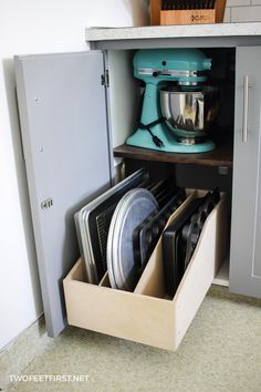 an open cabinet with dishes and mixers in it