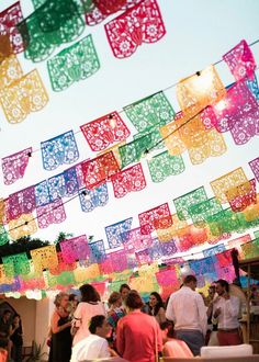 many people are standing under some colorful flags