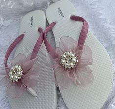 These beautiful white flip flops are hand wrapped in mauve satin ribbon, and adorned with a handmade matching organza flower with a rhinestone center. Ribbon color is mauve, if you are needing other colors of ribbon or decoration please contact me and will be happy to accommodate you! All flip flops are handmade to order and the production time is 5-7 business days and then please allow additional time for shipping. Amazing for beach, weddings, flower girl or a fancy event, you choose! Please ch Adjustable Pink Sandals For Wedding, Elegant Pink Summer Flip Flops, Pink Open Toe Lace-up Sandals For Beach, White Flower-shaped Elegant Sandals, Cheap Flower-shaped Beach Sandals, Bridesmaid Flip Flops, Elegant Flower-shaped Beach Sandals, Pink Crystal-embellished Sandals For Spring, Bridal Flip Flops