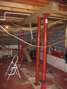 an unfinished room with red pipes and chairs